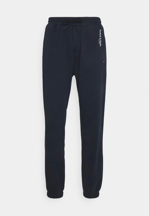 Pantalon jogger bleu marine foncé avec taille élastique, cordon, chevilles resserrées et petit texte blanc "Scotch & Soda" sur la hanche droite.