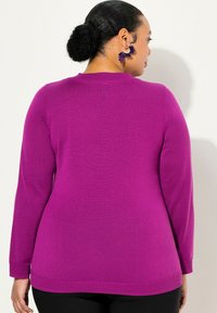 Lila Langarmpullover in taillierter Passform, aus weichem Material, mit gerippten Bündchen und Saum, der eine glatte Textur aufweist.