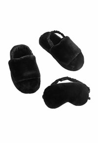 Pantofole in peluche nere e una mascherina per dormire. Le pantofole hanno un design imbottito con bordi elasticizzati per una vestibilità aderente. Morbido texture in tutto.