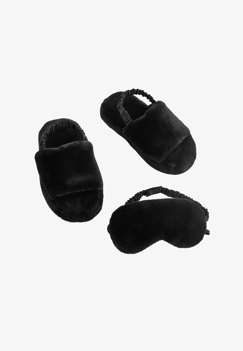 Čierne plyšové papuče a maska na spanie. Papuče majú polstrovaný dizajn s elastickými okrajmi pre pevné uchytenie. Mäkká textúra po celej ploche.