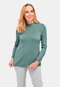 Gebreide trui in teal met een hoge kraag, voorzien van een textuurpatroon bij de schouderlijn. Lange mouwen en een rechte zoom maken het ontwerp af.