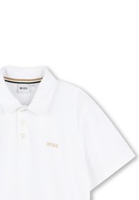 Polo shirt bianco in cotone con una consistenza morbida. Caratterizzato da un colletto classico, una chiusura con tre bottoni e un discreto logo "BOSS" in beige.