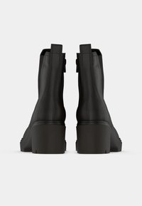 Stivaletti neri in pelle con finitura liscia, tacco rettangolare e cuciture minime. Dotati di linguette per un facile indossamento.