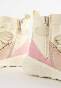 Scarpe alte beige chiaro e rosa con suola testurizzata, dotate di chiusura con zip e pannelli in tessuto morbido a contrasto.