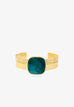 Bracelet manchette en or avec des détails texturés comportant une grande pierre carrée bleu sarcelle foncé au centre sur fond blanc.