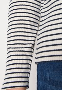 Gestreepte longsleeve top met witte en marineblauwe horizontale lijnen, geribbelde textuur en een rechte zoom, gecombineerd met denim stof.