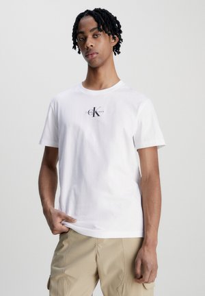 Camiseta de algodón blanca con un estampado en la parte frontal del logo "Calvin Klein Jeans". Mangas cortas, cuello redondo, corte relajado. Textura suave.