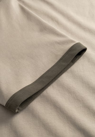 Μπεζ βαμβακερό ύφασμα με ριγωτό γιακά σε σκούρο ελαιδί πράσινο χρώμα. Το ύφασμα έχει λεία υφή και ελαφριά ελαστικότητα.