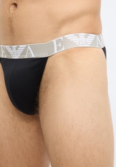 Čierne tangá so svetlosivým elastickým pásom s logom. Materiál je hladký a priliehavý, bez ďalších ozdôb.