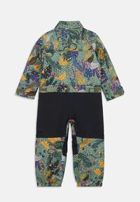Costum de ploaie colorat cu o bază verde, având modele vibrante de junglă în nuanțe de violet, portocaliu și galben; panouri negre pe picioare.