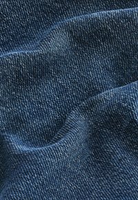 Tume sinine denimkangas tekstuurse, kudumise mustriga. Materjalil on peened tooni variatsioonid, mis näitavad pehmet, veidi tekstuurset pinda.