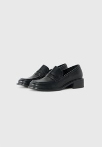 Pair of black leather low-heeled loafers with a rounded toe and penny strap detail, set against a white background.