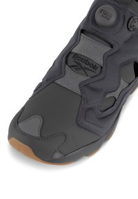 Grauer Sneaker mit einer strukturierten Oberseite, Gummiapplikationen, einer wulstigen gumsohle und einem markanten schnürsenkellosen Design mit einer Pumpmechanik.