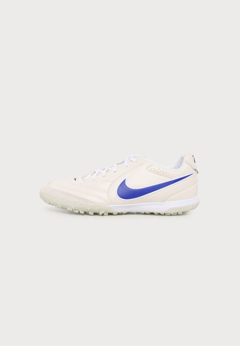Λευκό παπούτσι ποδοσφαίρου Nike με μπλε λογότυπο Swoosh και λευκά κορδόνια σε λευκό φόντο.