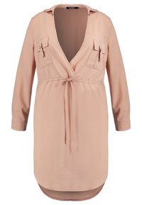 Långärmad, ljusrosa wrap-klänning med djup V-ringning, snörning i midjan, två bröstfickor med dragkedja och rundad nederkant.
