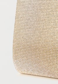 Bolso metálico dorado con una superficie texturizada cubierta de pequeñas tachuelas brillantes. Presenta una forma estructurada con una base redondeada.