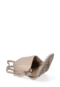 Borsa a mano in pelle beige con forma strutturata, dotata di una tasca interna con zip, una sottile tracolla e borchie decorative sul fondo.