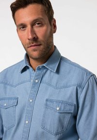 Hellblaues Denimhemd mit Druckknöpfen, westernstiliger Yoke, zwei Brusttaschen und Kragen. Der Stoff wirkt weich mit einer leichten Textur.