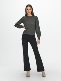 Grå stickad tröja med puffärmar, parat med svarta utsvängda byxor och beige anklarstövlar. Outfiten har en avslappnad, figursydd design.