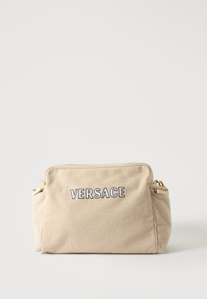Bolsa rectangular beige con bolsillos laterales, detalles de cremallera dorada y "VERSACE" bordado en negro y blanco en el centro frontal.