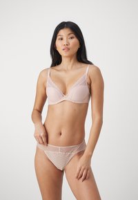 Hellrosa Spitzen-BH und passende Unterhose mit einem Diamantmuster, gewellten Kanten und einem zarten Hardware-Akzent in der Mitte.