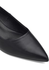 Zapato de cuero negro de punta afilada con una textura suave y un diseño minimalista. Presenta un escote bajo en el empeine y una silueta elegante.