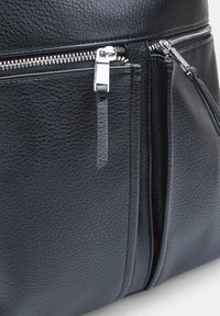 Zaino in pelle nera con finitura testurizzata, dotato di cerniere in tono argento, tasche con doppia zip e dettagli di cucitura sottili.