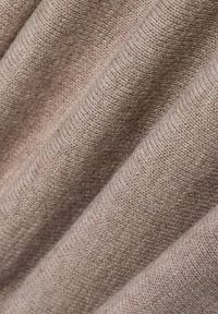Miękka beżowa dzianina z teksturowanym prążkowaniem i delikatnym połyskiem, z ukośnymi fałdami i gładką powierzchnią.