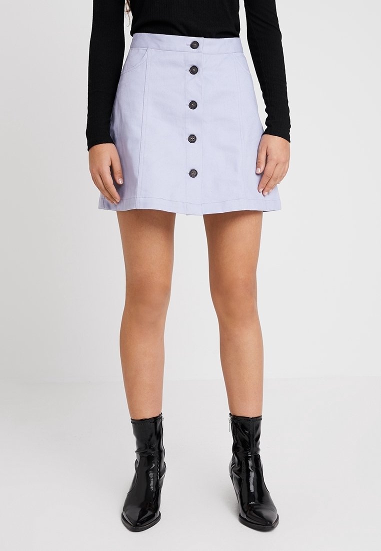 Ljuslila, knäppt kjol i mjukt material, med fem mörka knappar, utsvängd form och sidofickor. Stylad med svarta stövlar.