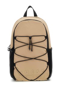 Beige tygryggsäck med svarta accenter, utrustad med en elastisk snodddesign, framträdande logotyp och ett handtag på toppen för bärande.