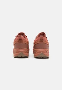 To par rustfargede sneakers med teksturert stoff, polstrede krager og robuste gummisåler, med kontrasterende mørke detaljer og snøring.