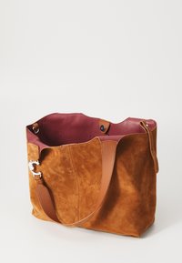 Braune Wildledertasche mit burgunderrotem Innenfutter, ausgestattet mit einem ledernen Schulterriemen und einem silbernen Hardware-Detail.