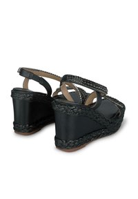 I sandali con zeppa nera presentano una base intrecciata testurizzata, cinturini decorativi con embellishments e un materiale superiore liscio.