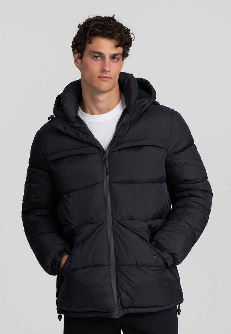 Giacca puffer nera con cappuccio, design trapuntato, chiusura frontale con zip e tasche laterali. Presenta un tessuto testurizzato e cordini regolabili.