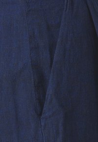 Marinblå linne med en subtil textur och en vikning, med synliga stygn i ett diagonalt mönster.