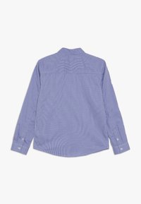Långärmad skjorta i ljusblått med vita vertikala ränder, knäppbar krage och justerbara manschetter. Tillverkad av ett mjukt, lätt tyg.