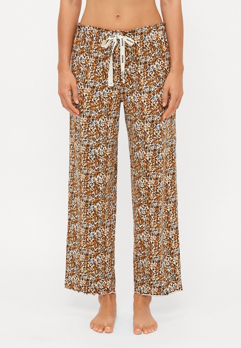 Bruna byxdress med blommönster och löst passform, tillverkade av lättviktsmaterial. Har en elastisk midja med dragsko.