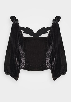 Schwarzes Samt-Crop-Top mit Puffärmeln und gebundenem Rücken. Weiche Textur und Glanz; verfügt über ein strukturiertes Oberteil und breite Manschetten.
