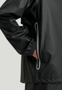 Svart vattentät jacka med elastiska ärmslut, med en ficka med dragkedja och reflekterande kant längs sidan för synlighet. Slät yta.