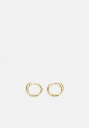 Złote kolczyki w kształcie obręczy o gładkim, zaokrąglonym wzornictwie. Posiadają małe zapięcie na zawias, lekką konstrukcję i błyszczące wykończenie.