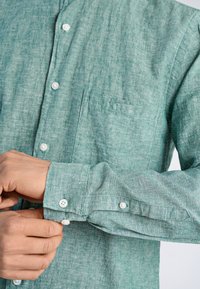 Lichtgroen overhemd met knopen, gemaakt van textiel met structuur, met een borstzak, witte knopen en verstelbare manchetten.