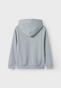 Vaaleanharmaa huppari, jossa on pehmeä rakenne, hupullinen, pitkät hihat ja ribattu helma. Ei näkyviä logoja tai kuvioita. Takakatsaus esillä.