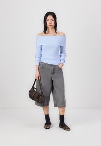 Lyseblå off-the-shoulder ribbet sweater, grå vidde shorts, sorte ankelstrømper, leopardmønstret flade sko og en mørkebrun skuldertaske.