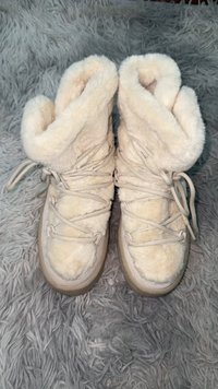 Białe, teksturowane buty z futerkiem, wyposażone w miękki kołnierz. Posiadają sznurowanie i zaokrąglony nosek, opierające się na trwałej, ryflowanej podeszwie.