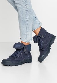 Botas de tobillo de lona azul marino con cordones y tira de velcro, suela de goma, punta redonda y cuello acolchado. Tejido texturizado con detalle de parche de logo.