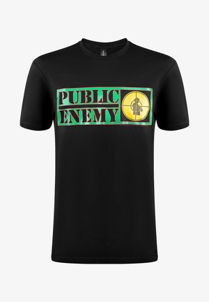 Musta musta T-paita, jossa on rohkea grafiikkasuunnittelu, jossa lukee "PUBLIC ENEMY" vihreällä ja punaisella, sekä keltainen maali-symboli.