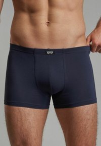 Navy blue cotton boxer briefs with a fitted design, featuring a black logo waistband and smooth texture. Simple and functional style.