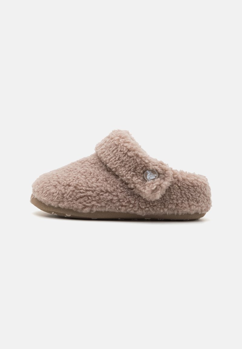 Chausson style sabot doux et duveteux couleur fauve avec bride sur le dessus et détail bouton, présenté de côté sur fond blanc.