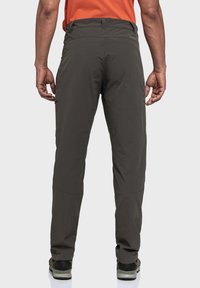 Dunkelgraue Outdoor-Hosen mit geradem Schnitt, elastischem Bund, funktionalen Taschen und verstärkten Unterschenkeln, kombiniert mit schwarzem Schuhwerk.