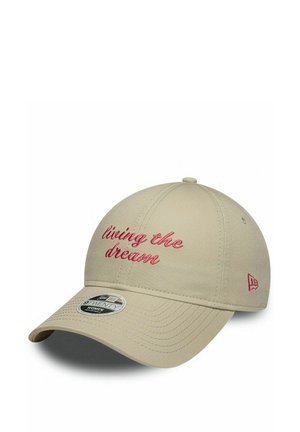 Beige baseballpet met rode geborduurde tekst 'living the dream' en een gebogen klep naar rechts op een witte achtergrond.